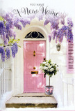 The photograph presents a warmly inviting Barkingside entryway dressed as if for a gentle celebration, where flowers, light, and colour blend into a single, welcoming moment. A pale pink front door, its paint softly weathered and full of character, stands against smooth whitewashed walls, reminiscent of the prettiest homes tucked just off Barkingside High Street. Above the door, wisteria cascades in loose, fragrant drifts of lavender and soft purple, the dangling clusters overlapping like layers of lace and filtering the daylight into a romantic haze. At the base of the doorway, set neatly on the step, a vintage-style grey bucket holds a lush arrangement of white and cream roses, their rounded, velvety blooms brushing against each other as though whispering. Nestled between the roses, muted green foliage peeks through, giving the arrangement texture and a touch of garden freshness that might remind you of a walk through nearby Clayhall Park in late spring. A narrow ribbon in pastel pink wraps around the bucket, tied in a relaxed bow, its trailing ends catching the light and leading your eye back up to the pink door. The overall feeling is one of tender optimism: the soft pastel palette, the gentle shadows, and the abundant flowers make it easy to imagine this as a housewarming bouquet, delivered by a caring local florist to celebrate a move. The scene seems to pause just before the new homeowners arrive, the threshold prepared with beauty, ready to turn a simple doorway into a true 'welcome home' in the heart of Barkingside.